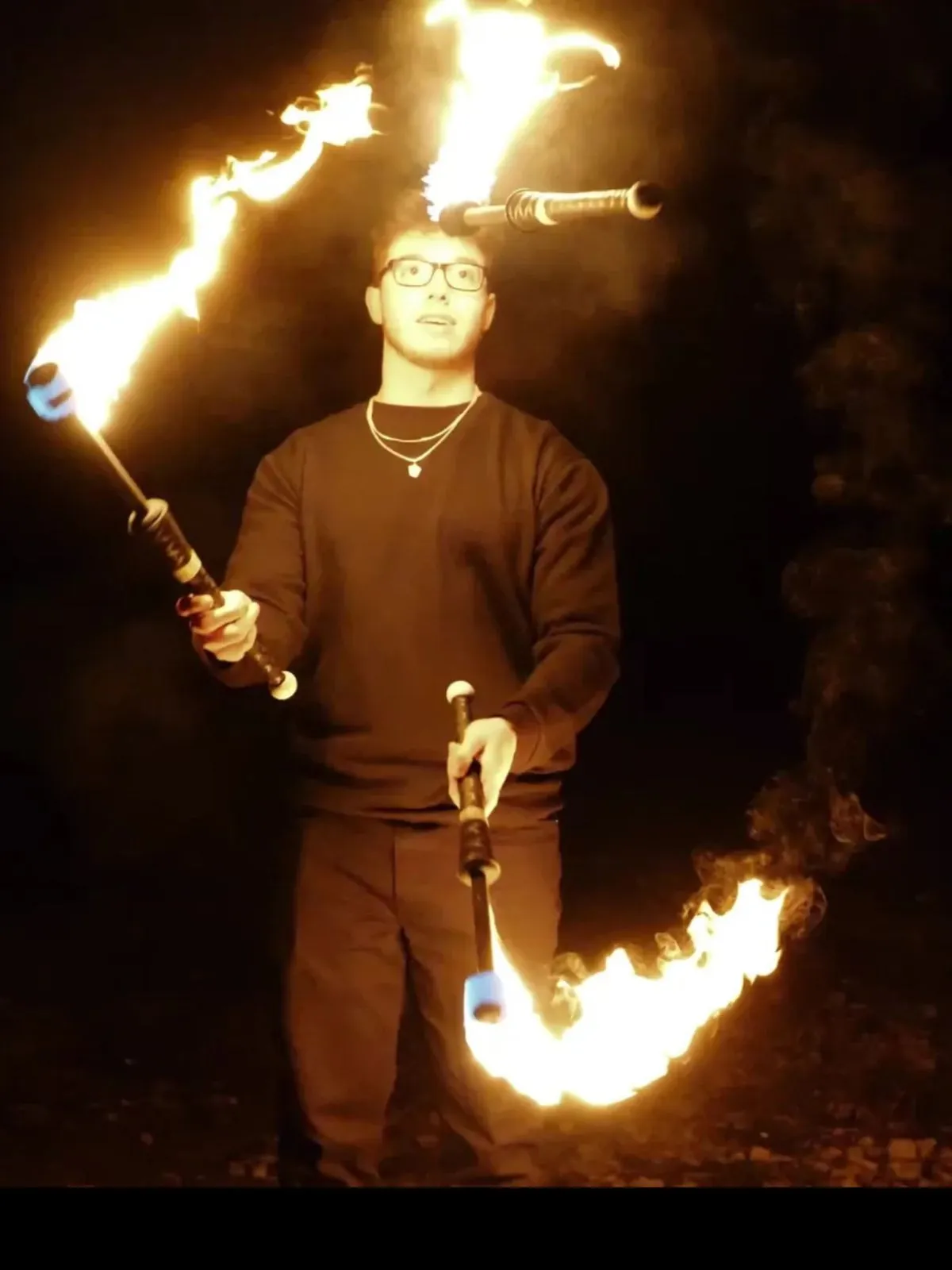 Fire juggler performing with blazing clubs at outdoor Toronto festival event